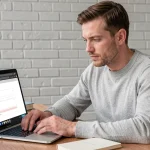 Homme configurant un compte email laposte.net sur un client de messagerie Outlook depuis son bureau à domicile