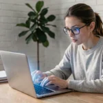 Femme utilisant une nouvelle interface de plateforme en ligne sur son ordinateur portable dans un bureau à domicile moderne