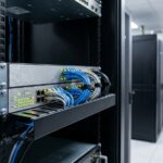 Switch manageable professionnel monté en rack dans une salle serveur d'entreprise avec câbles réseau Cat6 et voyants LED colorés